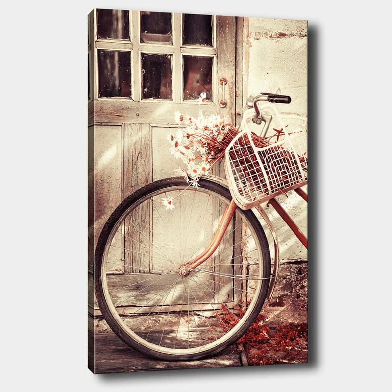 Lerretsbilde 70x100 cm - Sykkel med en kurv fylt med blomster foran en gammel dør, Grå / Brun / Hvit