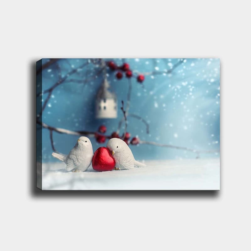 Lerretsbilde 70x100 cm - To fugler som holder et rødt hjerte sammen i et vinterlig miljø, Hvit / Rød / Blå