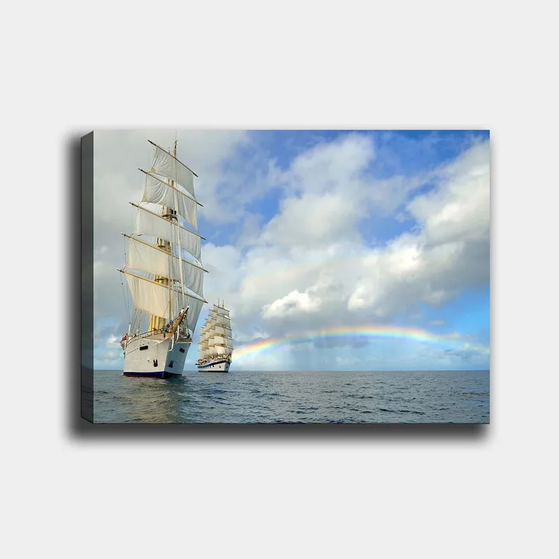 Lerretsbilde 70x100 cm - To seilbåter som navigerer gjennom et rolig hav under en blå himmel med skyer og en regnbue, Hvit / Blå / Grå
