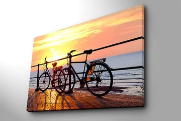Lerretsbilde 70x100 cm - To sykler som står på en brygge ved solnedgang over havet - Oransje / Svart / Gul - Interiør - Maleri & posters - Lerretsbilder