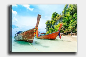 Lerretsbilde 70x100 cm - To tradisjonelle thailandske langbåter på en strand med steiner og frodig vegetasjon i bakgrunnen - Brun / Grønn / Blå - Interiør - Maleri & posters - Lerretsbilder