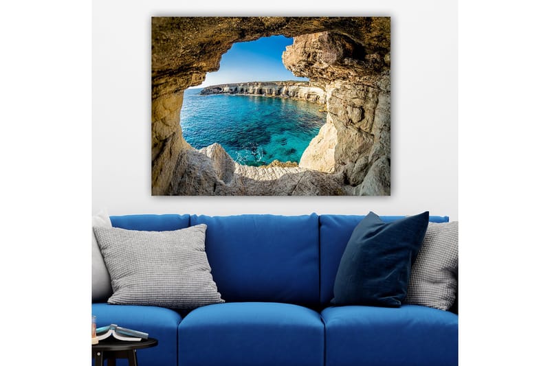 Lerretsbilde 70x100 cm - Utsikt gjennom en klippeåpning mot en klar blå strand - Blå / Beige / Hvit - Interiør - Maleri & posters - Lerretsbilder
