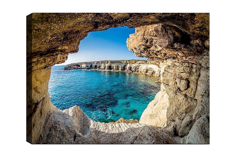 Lerretsbilde 70x100 cm - Utsikt gjennom en klippeåpning mot en klar blå strand, Blå / Beige / Hvit
