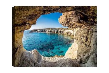 Lerretsbilde 70x100 cm - Utsikt gjennom en klippeåpning mot en klar blå strand - Blå / Beige / Hvit - Interiør - Maleri & posters - Lerretsbilder