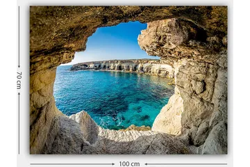 Lerretsbilde 70x100 cm - Utsikt gjennom en klippeåpning mot en klar blå strand - Blå / Beige / Hvit - Interiør - Maleri & posters - Lerretsbilder