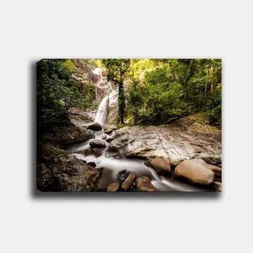 Lerretsbilde 70x100 cm - Vakker fossescene omgitt av frodig grøntområde og steinblokker - Grønn / Grå / Brun - Interiør - Maleri & posters - Lerretsbilder