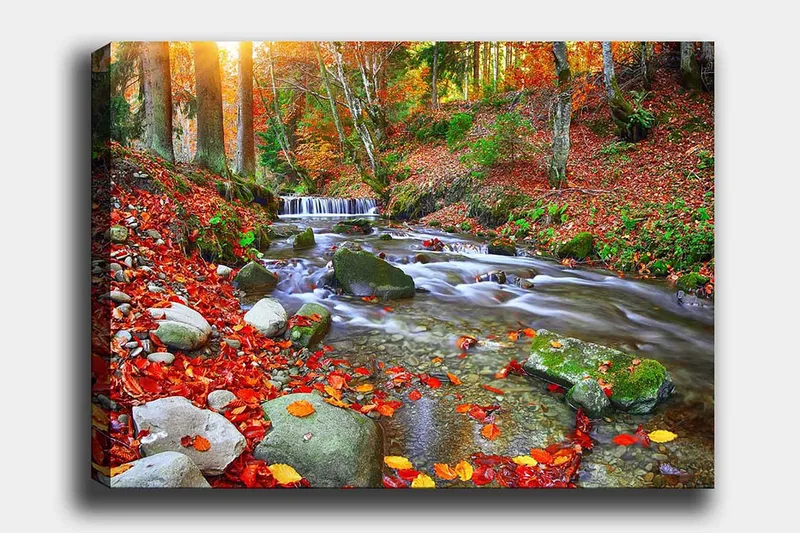 Lerretsbilde 70x100 cm - Vakker høstscene med en rislende bekk omgitt av fargerike høstblader, Rød / Grønn / Brun