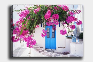 Lerretsbilde 70x100 cm - Vakker hvit bygning med en blå dør omgitt av lilla blomster - Lilla / Blå / Grønn - Interiør - Maleri & posters - Lerretsbilder