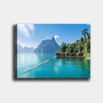 Lerretsbilde 70x100 cm - Vakker innsjø med hytter ved vannet, omgitt av majestetiske fjell og frodig skog - Turkis / Grønn / Brun - Interiør - Maleri & posters - Lerretsbilder