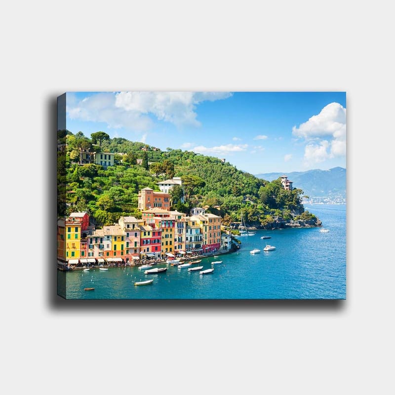 Lerretsbilde 70x100 cm - Vakker kystby med fargerike hus ved sjøen, omgitt av frodige åser, Blå / Grønn / Gul