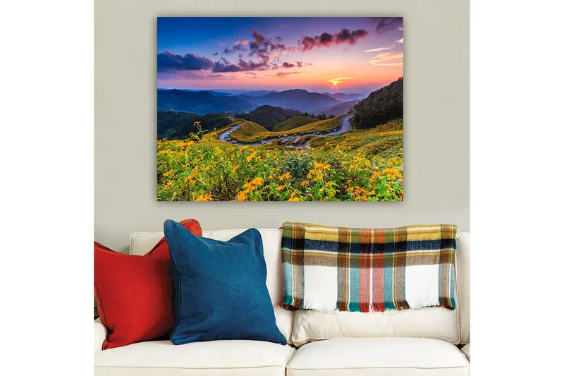 Lerretsbilde 70x100 cm - Vakker solnedgang over en blomstrende dal med svingete veier og fjell i bakgrunnen - Gul / Grønn / Blå - Interiør - Maleri & posters - Lerretsbilder