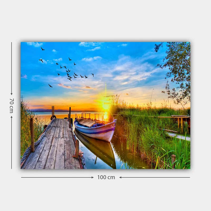 Lerretsbilde 70x100 cm - Vakker solnedgang over en rolig innsjø med en båt ved en trebrygge omgitt av grøntområder - Blå / Oransje / Grønn - Interiør - Maleri & posters - Lerretsbilder