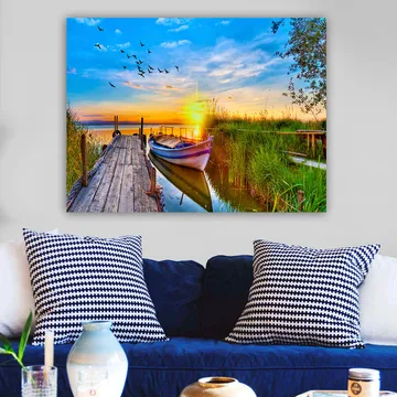 Lerretsbilde 70x100 cm - Vakker solnedgang over en rolig innsjø med en båt ved en trebrygge omgitt av grøntområder - Blå / Oransje / Grønn - Interiør - Maleri & posters - Lerretsbilder