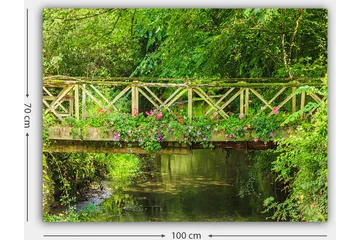 Lerretsbilde 70x100 cm - Vakker trebro omgitt av grøntområder og blomster ved en rolig vannflate - Grønn / Rosa / Brun - Interiør - Maleri & posters - Lerretsbilder