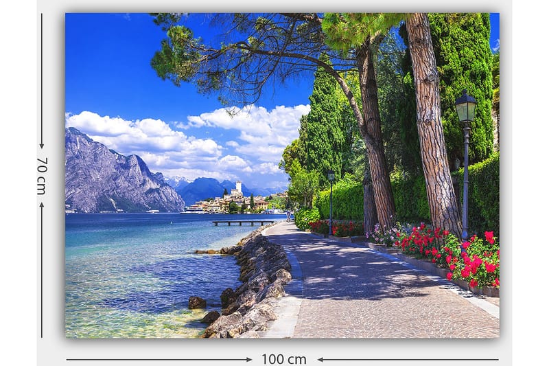 Lerretsbilde 70x100 cm - Vakker promenade med trær og blomster ved en innsjø, omgitt av fjell og en pittoresk by i bakgrunnen - Blå / Grønn / Rød - Interiør - Maleri & posters - Lerretsbilder