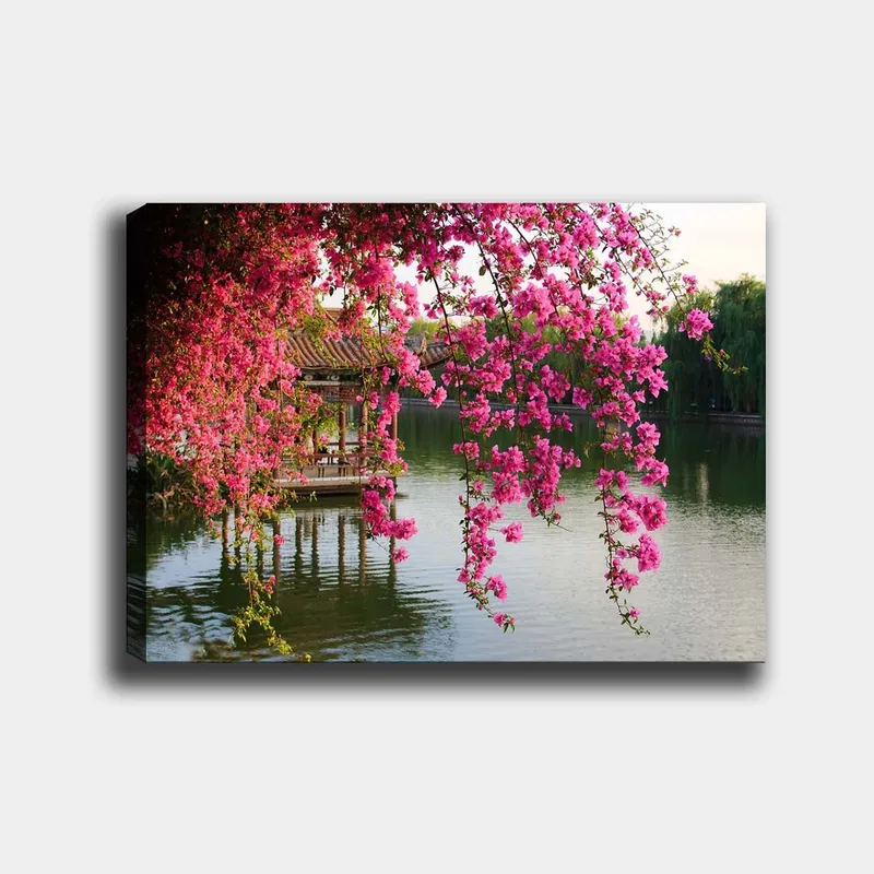 Lerretsbilde 70x100 cm - Vakker paviljong omgitt av blomstrende bougainvillea ved en stille innsjø, Rosa / Grønn / Blå