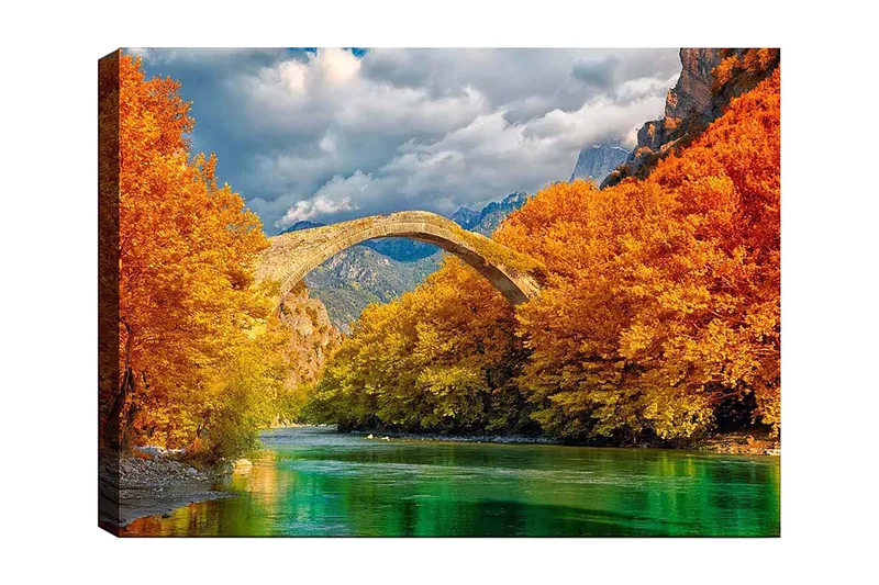 Lerretsbilde 70x100 cm - Vakkert høstlandskap med en gammel steinbro som strekker seg over en glitrende elv omgitt av fargerike trær, Oransje / Grønn / Blå