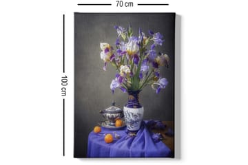 Lerretsbilde 70x100 cm - Vakkert stilleben med en vase fylt med lilla irisblomster og en skål med appelsiner - Lilla / Hvit / Oransje - Interiør - Maleri & posters - Lerretsbilder