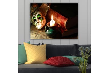 Lerretsbilde 70x100 cm - Venetiansk maske i fokus med et brennende stearinlys og gamle bøker i bakgrunnen - Grønn / Brun / Hvit - Interiør - Maleri & posters - Lerretsbilder