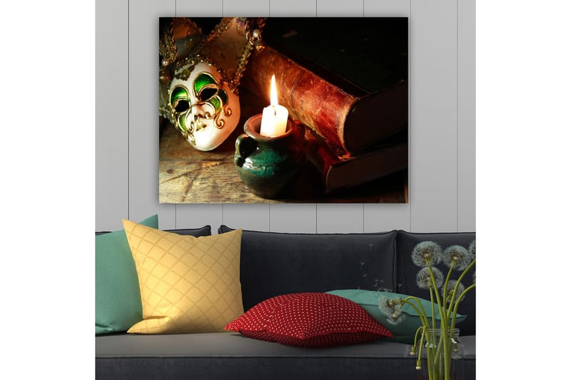 Lerretsbilde 70x100 cm - Venetiansk maske i fokus med et brennende stearinlys og gamle bøker i bakgrunnen - Grønn / Brun / Hvit - Interiør - Maleri & posters - Lerretsbilder