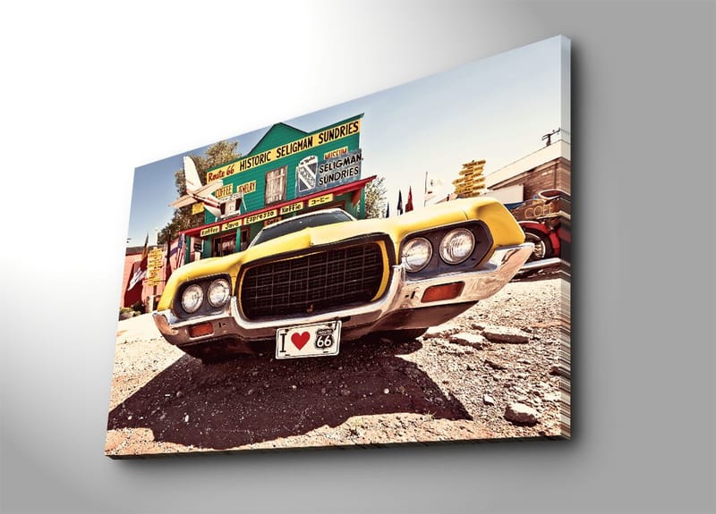 Lerretsbilde 70x100 cm - Veteranbil i gult foran et nostalgisk veiskilt langs Route 66, Gul / Svart / Sølv