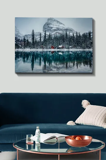 Lerretsbilde 70x100 cm - Vinterlandskap med snødekte fjell og en speilblank innsjø omgitt av grantrær og røde hytter - Mørk grønn / Blå / Hvit - Interiør - Maleri & posters - Lerretsbilder