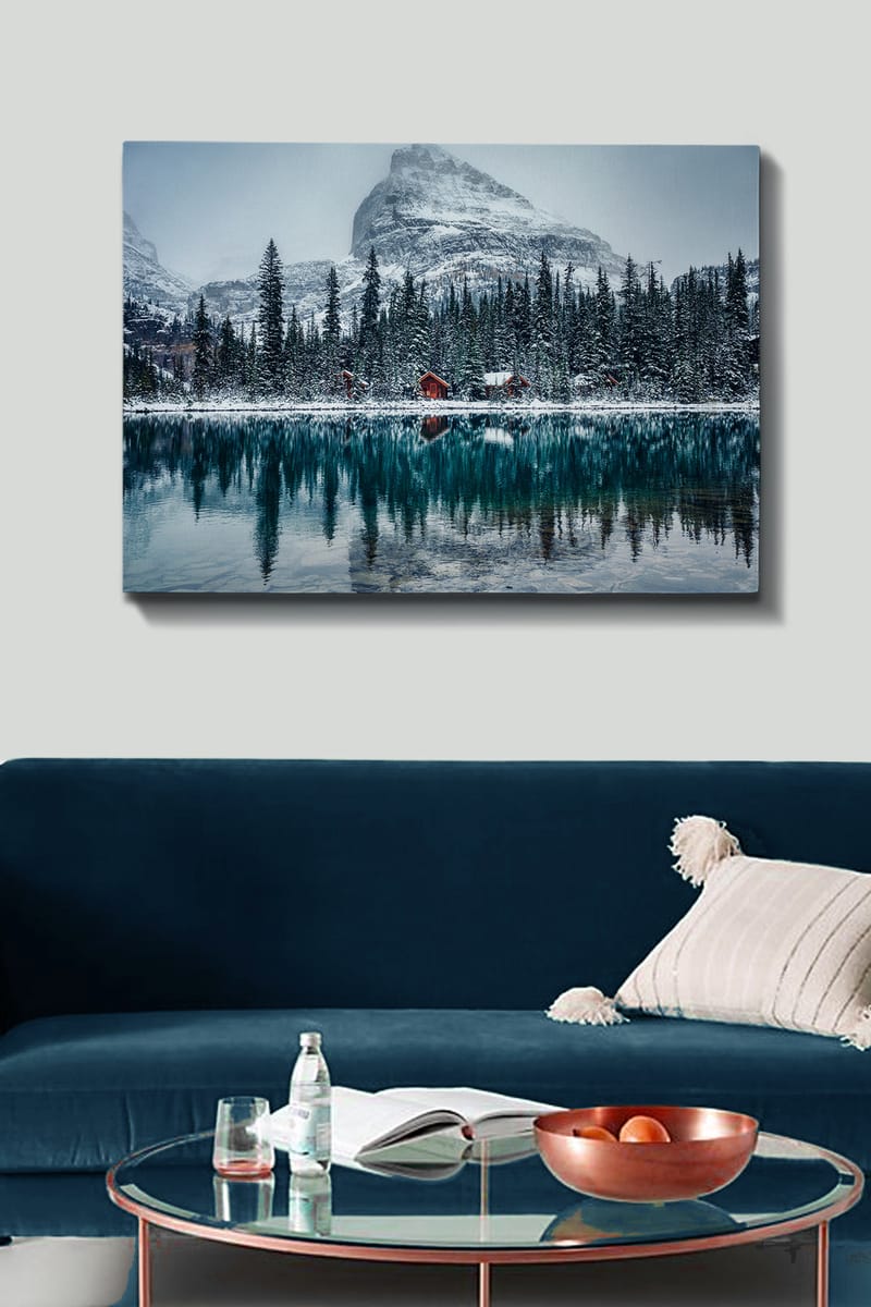 Lerretsbilde 70x100 cm - Vinterlandskap med snødekte fjell og en speilblank innsjø omgitt av grantrær og røde hytter - Mørk grønn / Blå / Hvit - Interiør - Maleri & posters - Lerretsbilder