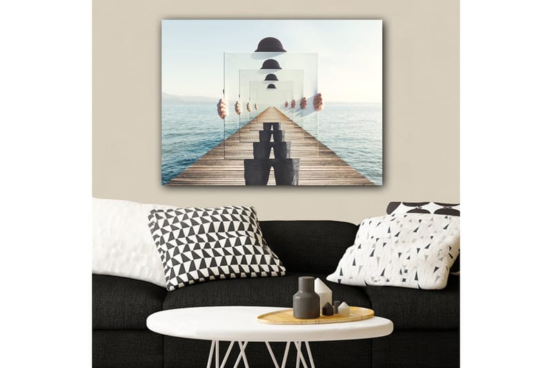Lerretsbilde 70x100 cm - Person som holder opp flere gjennomsiktige paneler som skaper en illusjon av dybde og perspektiv på en brygge ved vannet - Blå / Svart / Hvit - Interiør - Maleri & posters - Lerretsbilder