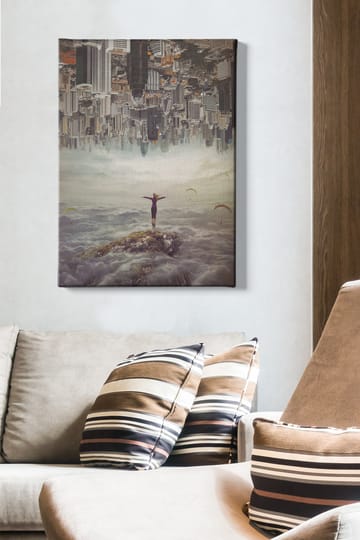 Lerretsbilde 70x100 cm - Person som står med utstrakte armer på en klippe over skyene, med en by i bakgrunnen som er opp ned - Grå / Beige / Mørk blå - Interiør - Maleri & posters - Lerretsbilder