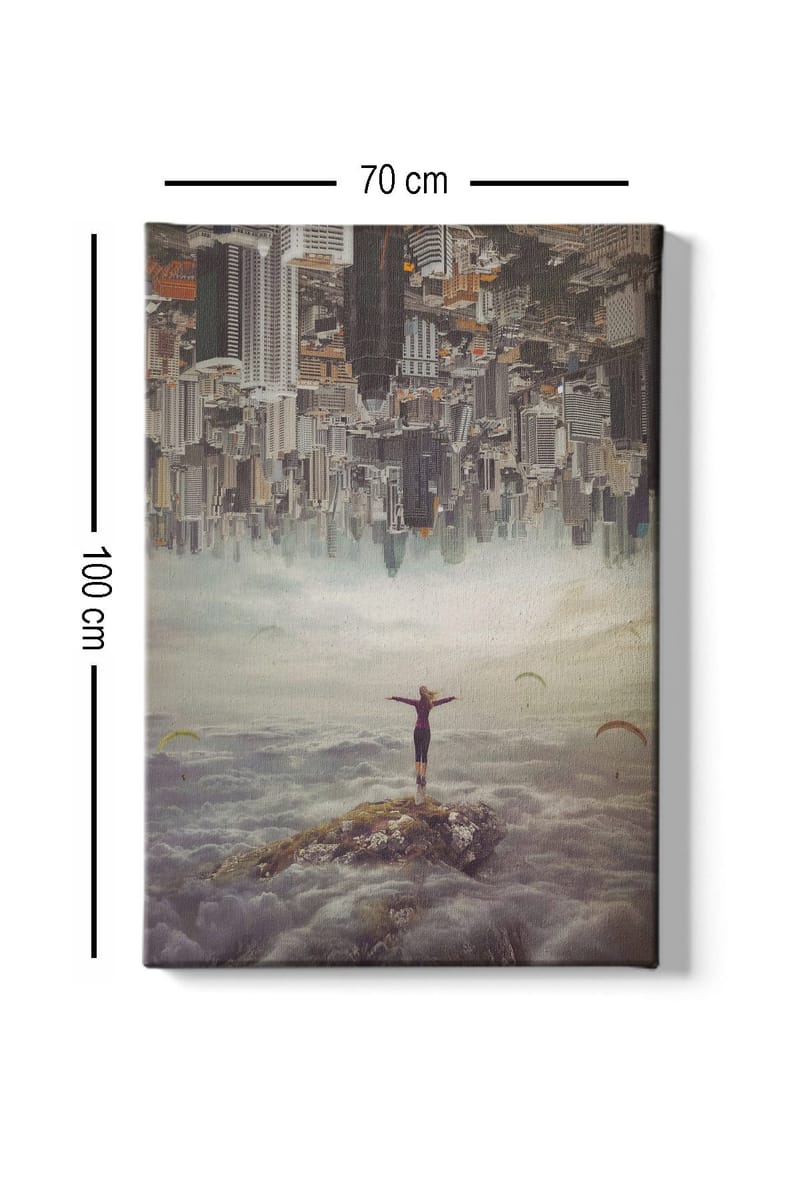 Lerretsbilde 70x100 cm - Person som står med utstrakte armer på en klippe over skyene, med en by i bakgrunnen som er opp ned - Grå / Beige / Mørk blå - Interiør - Maleri & posters - Lerretsbilder
