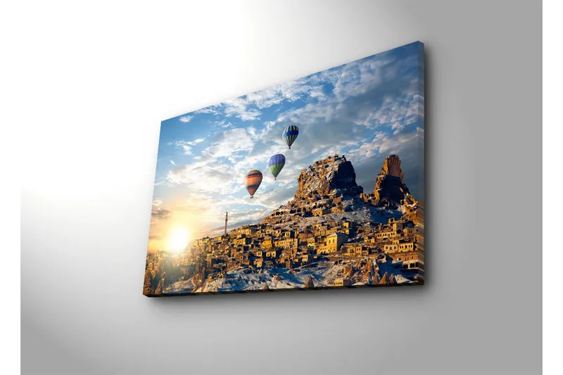 Lerretsbilde 70x45 cm - Fargerike varmluftsballonger svever over en pittoresk fjellandsby ved soloppgang - Gull / Blå / Oransje - Interiør - Maleri & posters - Lerretsbilder