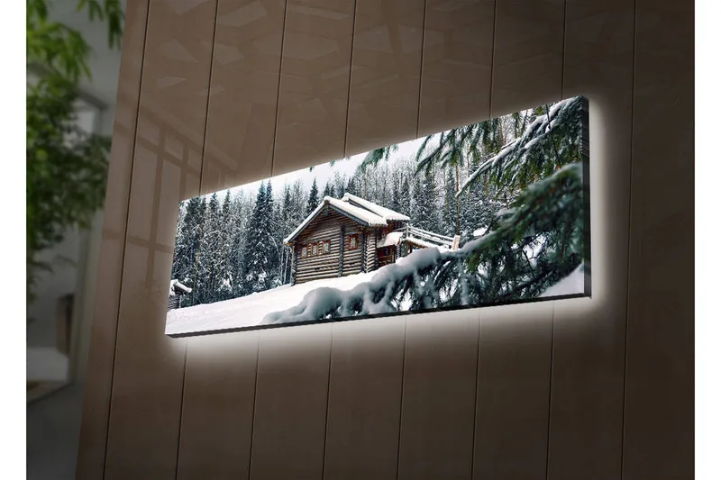 Lerretsbilde med LED-belysning 30x90 cm - Vinterlandskap med hytte omgitt av snø og grantrær, Hvit / Grønn / Brun