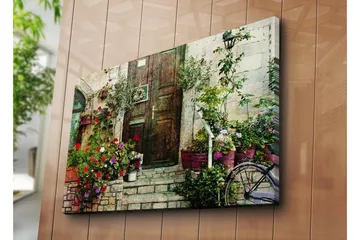 Stort lerretsbilde 100x70 cm - Vakker dør omgitt av fargerike blomster og grøntområder - Rød / Grønn / Lilla - Interiør - Maleri & posters - Lerretsbilder